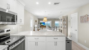 A modern kitchen with white cabinetry, a large island, and stainless steel appliances. - Sparkling Views from this two bedroom, two bathroom Gulf Front Sandy Bend 8 (Sanibel)