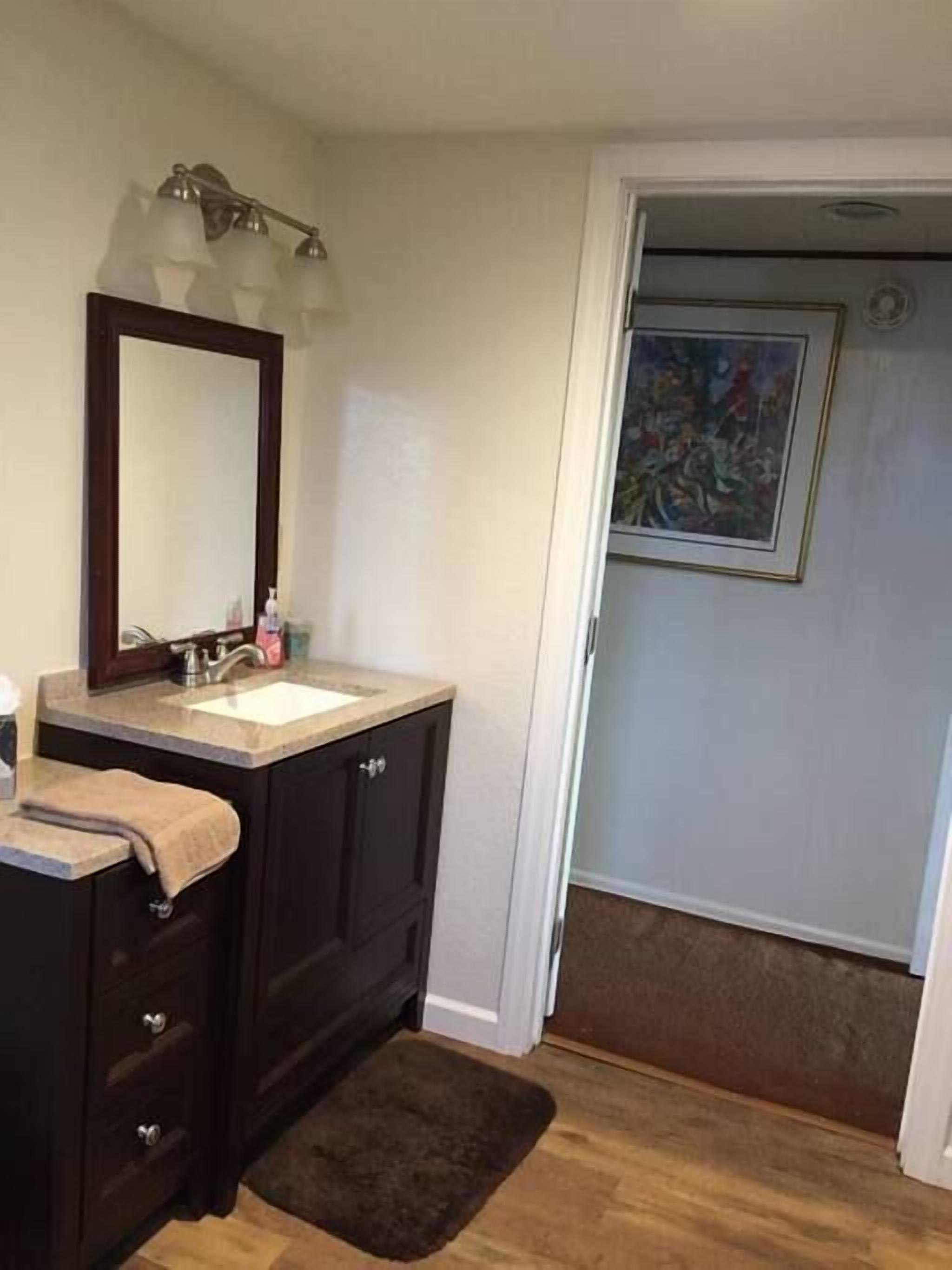 A bathroom with a dark wooden vanity, a mirror, and a sink.