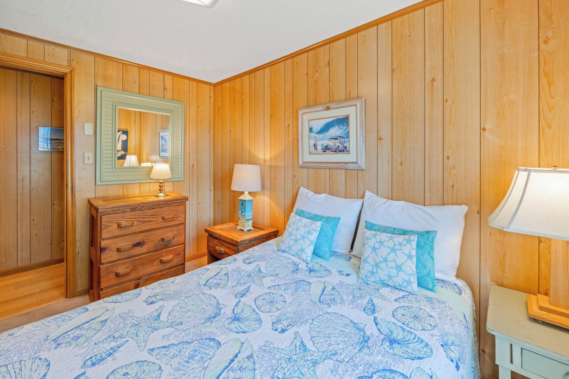A wooden-paneled room with a bed, dresser, and nightstands.