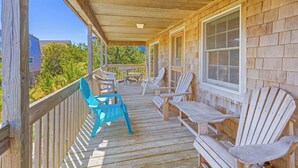 A wooden deck with outdoor seating, including chairs and tables, overlooking a residential area. - Oceanview Dog Friendly Home in Avon w/ Grill, Games. Only 3 Lots From Beach! (Avon)