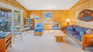 A cozy living room with a wooden interior, a sofa, a coffee table, and a bookshelf. - Oceanview Dog Friendly Home in Avon w/ Grill, Games. Only 3 Lots From Beach! (Avon)