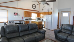 A spacious living room with leather sofas, a glass coffee table, and a ceiling fan. - Last Minute, low price/Great Ocean view/ Pool/ Ping Pong table/Fenced pet area (Nags Head)