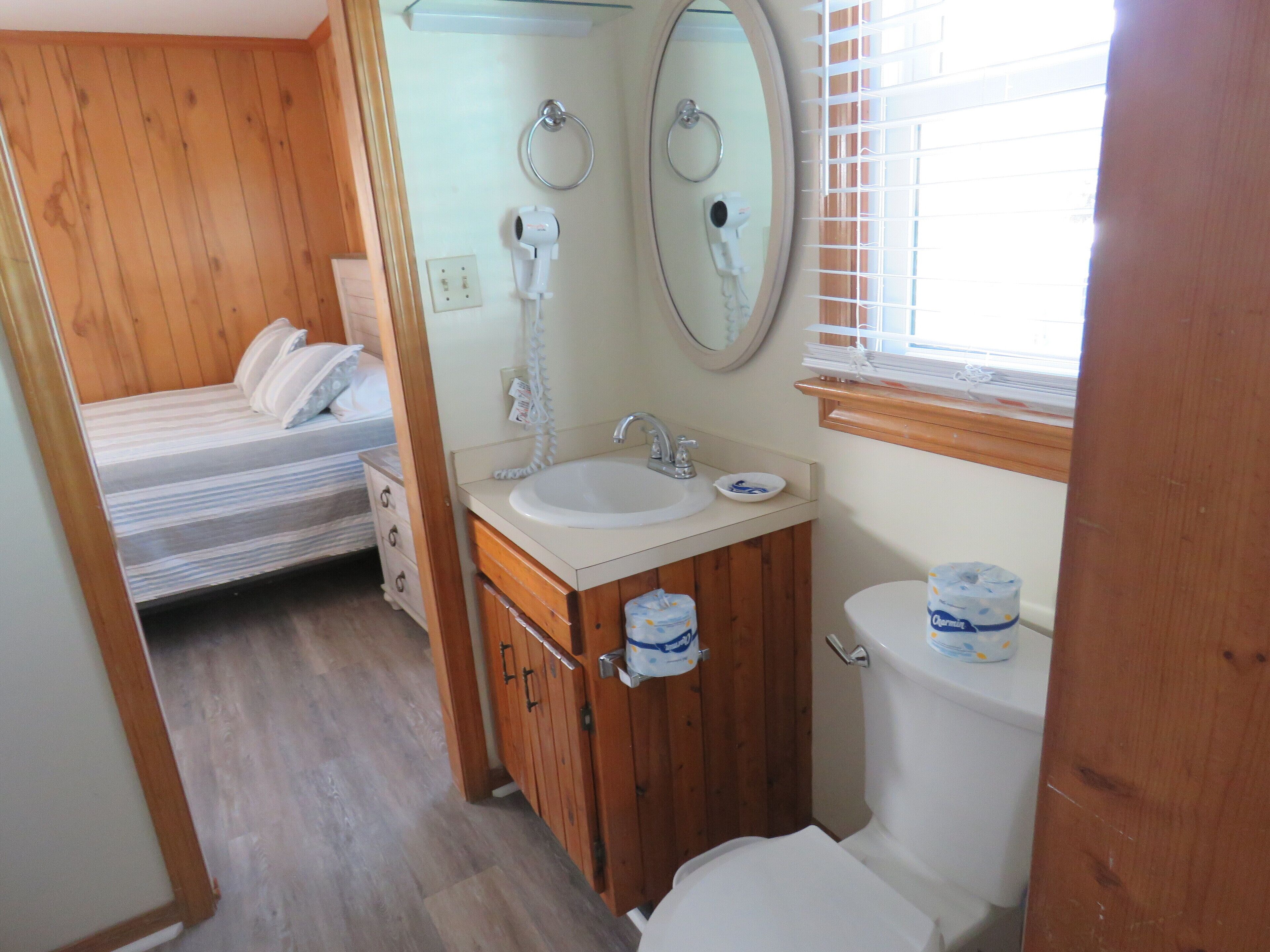 Une petite salle de bain avec un meuble-lavabo en bois, un évier, des toilettes et un miroir.