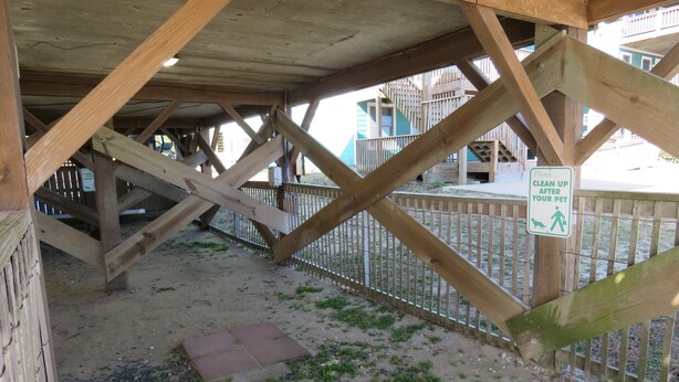 A wooden structure with a metal fence and a sign requesting pet owners to clean up after their pets. - Last Minute, low price/Great Ocean view/ Pool/ Ping Pong table/Fenced pet area (Nags Head)