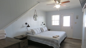 A bedroom with a bed, a nightstand, a dresser, a ceiling fan, a window, and a door. - Last Minute, low price/Great Ocean view/ Pool/ Ping Pong table/Fenced pet area (Nags Head)