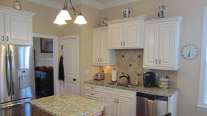 A kitchen with white cabinets, stainless steel appliances, granite countertops, and a tiled backsplash.
