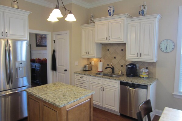 A kitchen with white cabinets, stainless steel appliances, granite countertops, and a tiled backsplash.