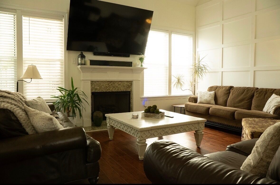 A living room with a fireplace, a television mounted above it, and a sofa.