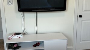 A television mounted on a white wall, with a white entertainment unit below it containing a few toys and a remote control. - Great reviews! Available for Masters Tournament (Evans)