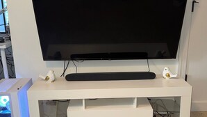 A white entertainment unit with a flat-screen TV, a keyboard, and a mouse.