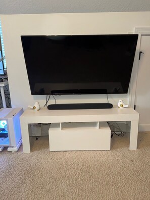 A white entertainment unit with a flat-screen TV, a keyboard, and a mouse.