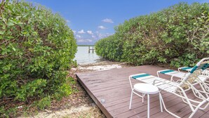 Eine Holzterrasse mit Liegestühlen und Blick auf das Wasser.