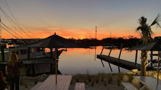 Een restaurant aan het water met terras en uitzicht op de zonsondergang.