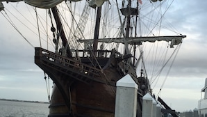 Een groot schip afgemeerd aan een steiger, met zichtbare masten en lijnen.