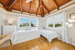A bedroom with two beds, a desk, a nightstand, and large windows with curtains. - P46 - Beautiful updated home on the Gulf side with pool and dock! (Marathon)