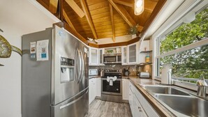 A kitchen with stainless steel appliances, a wooden ceiling, and a view of trees outside. - P46 - Beautiful updated home on the Gulf side with pool and dock! (Marathon)