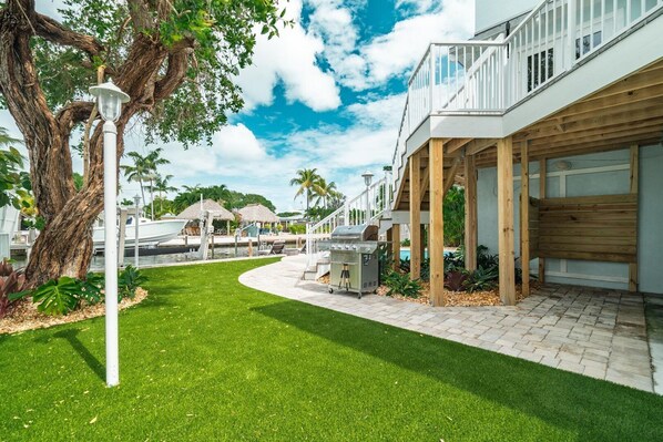 A waterfront property with a covered patio, outdoor grill, and a view of the marina. - P46 - Beautiful updated home on the Gulf side with pool and dock! (Marathon)