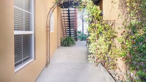 A narrow alleyway with a brick wall on one side and a window on the other. There is a wooden structure with a metal archway in the center. -  Downtown Napa!  Unit B Walk to Everything! (Napa)