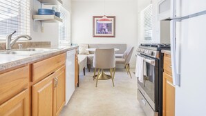 A modern kitchen with wooden cabinets, a granite countertop, a built-in oven, and a dining area with a round table and chairs. -  Downtown Napa!  Unit B Walk to Everything! (Napa)