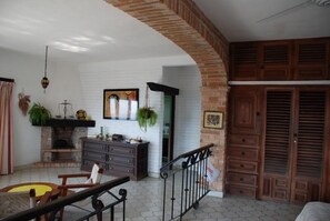 A room with a fireplace, wooden cabinets, a hanging plant, and a bed.