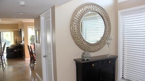 A hallway with a black cabinet, a decorative mirror, and a door leading to a dining area. - Beautiful Villa with Loft - 6 Passenger Golf Cart Included (Miramar Beach)