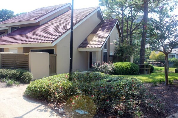 A residential house with a sloped roof, a front entrance, and a well-maintained garden with various plants and shrubs. - Beautiful Villa with Loft - 6 Passenger Golf Cart Included (Miramar Beach)