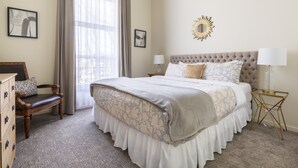 A bedroom with a large bed, a wooden chair, a dresser, and a window with curtains. - Downtown Napa!  Unit C Walk to Everything!  (Napa)