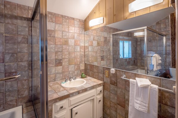 Une salle de bain avec une douche à parois de verre, un lavabo avec un miroir au-dessus et une serviette suspendue à un porte-serviettes.