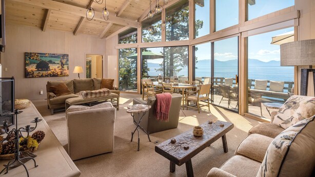 Un salón espacioso con un amplio ventanal que ofrece vistas panorámicas, amueblado con sofás, una mesa de centro y una zona de comedor.