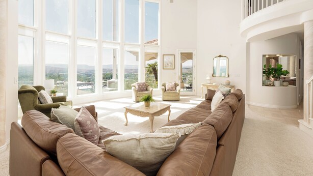 A spacious living room with a large window, a brown leather sofa, a coffee table, and a view of the city. - The Skyline Villa - Family Getaway Heaven in the Heart of Saint George, UT (St George)