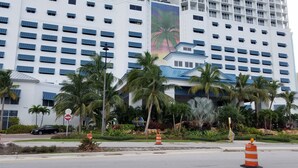 Un hotel de varios pisos, con numerosas ventanas y un llamativo mural de una palmera.