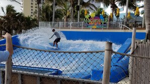 Un parque acuático con un hombre surfeando una ola.