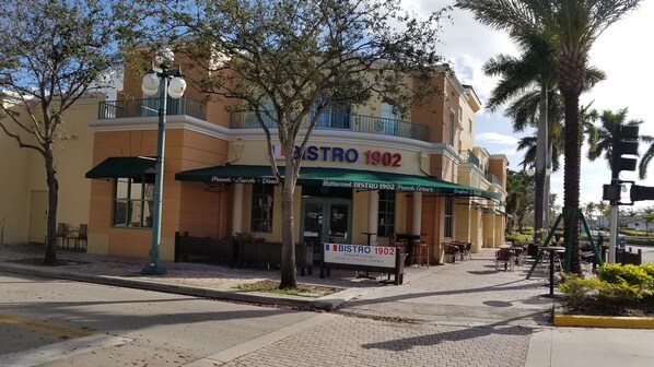 A restaurant named Bistro 1902 with outdoor seating and a green awning.