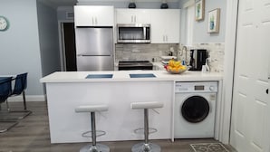 Una cocina moderna con una isla central, electrodomésticos de acero inoxidable y lavadora integrada.