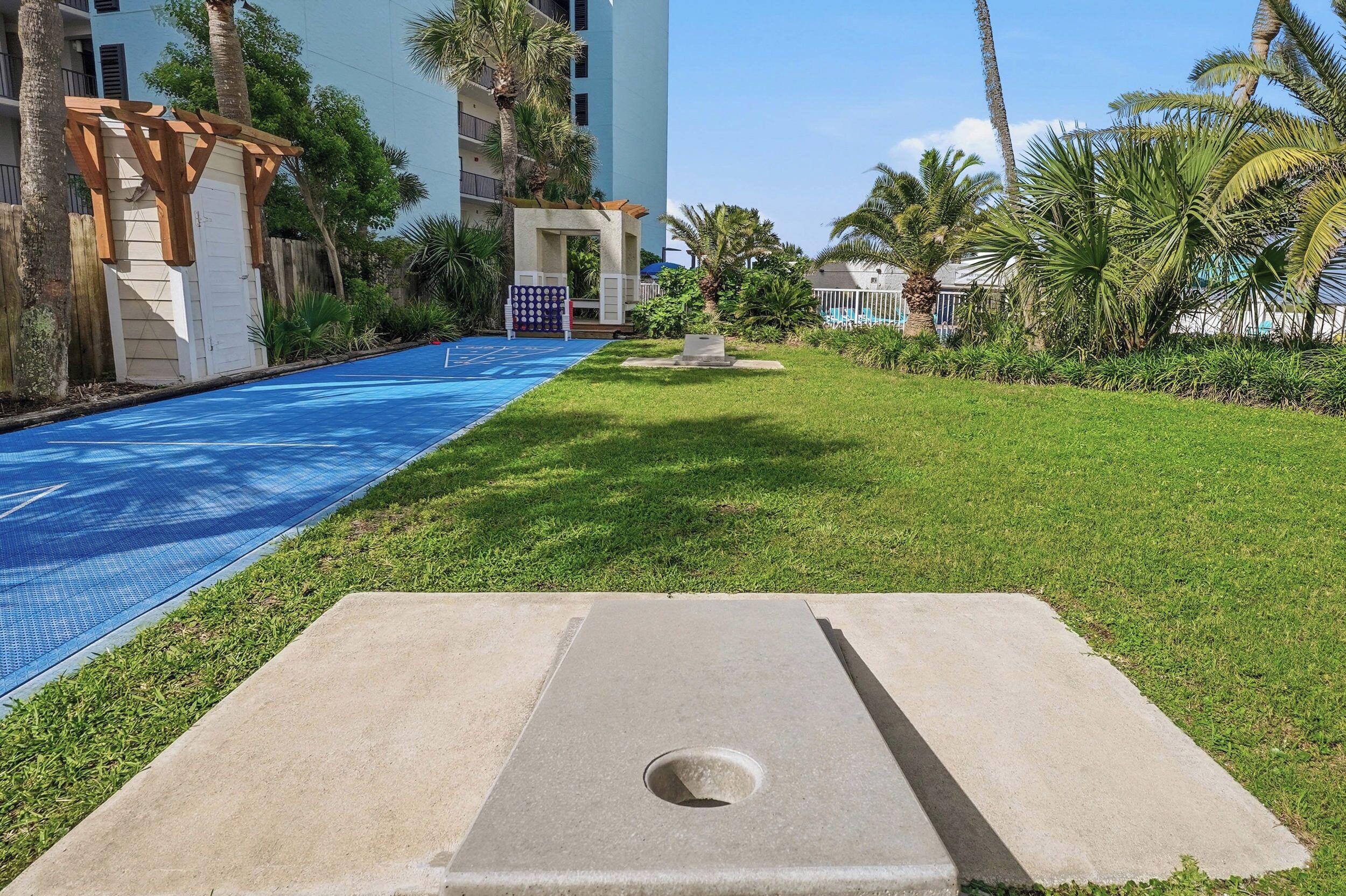 Un espace piscine avec un revêtement de carrelage bleu, une structure en béton au premier plan et un bâtiment doté de balcons en arrière-plan.