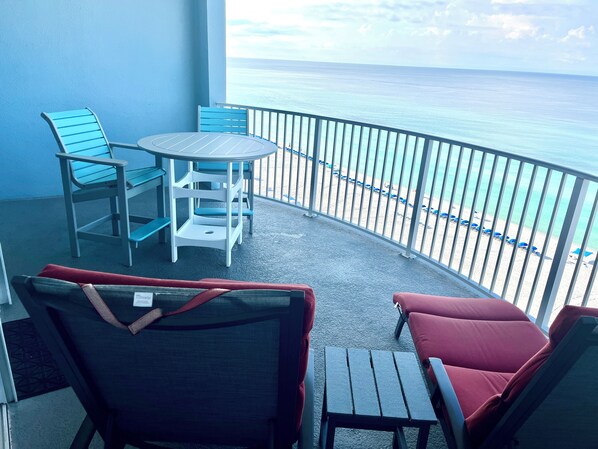 Ein Balkon mit Tisch und Stühlen mit Blick auf einen Strand.