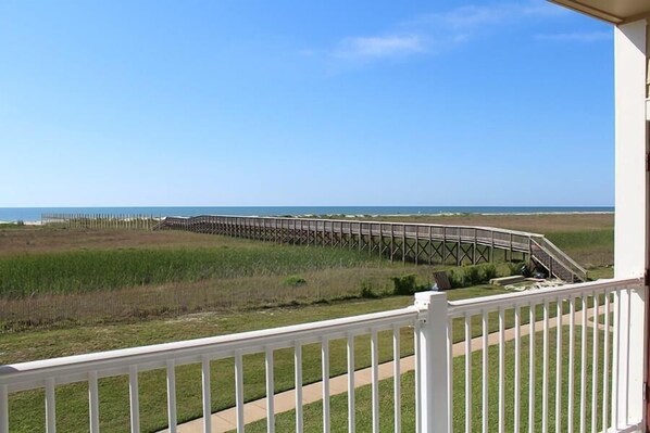 A balcony with a view of a beach and a wooden boardwalk. - Endless Summer -Beach Front-Dune Walkover- 3BD/2BA. Sleeps 9. (Galveston)