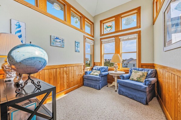 A room with a globe on a table, two blue sofas, a lamp, and framed artwork on the walls. - Semi-Oceanfront Home w/ Pool, Hot Tub, Elevator, Cabana w/ Tiki Bar, Game Room (Salvo)