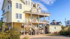 A multi-story building with a balcony, a basketball hoop, and a sign indicating a free sound system. - Semi-Oceanfront Home w/ Pool, Hot Tub, Elevator, Cabana w/ Tiki Bar, Game Room (Salvo)