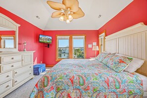 A bedroom with a large bed, a dresser, a television, and a window with a view of buildings. - Semi-Oceanfront Home w/ Pool, Hot Tub, Elevator, Cabana w/ Tiki Bar, Game Room (Salvo)