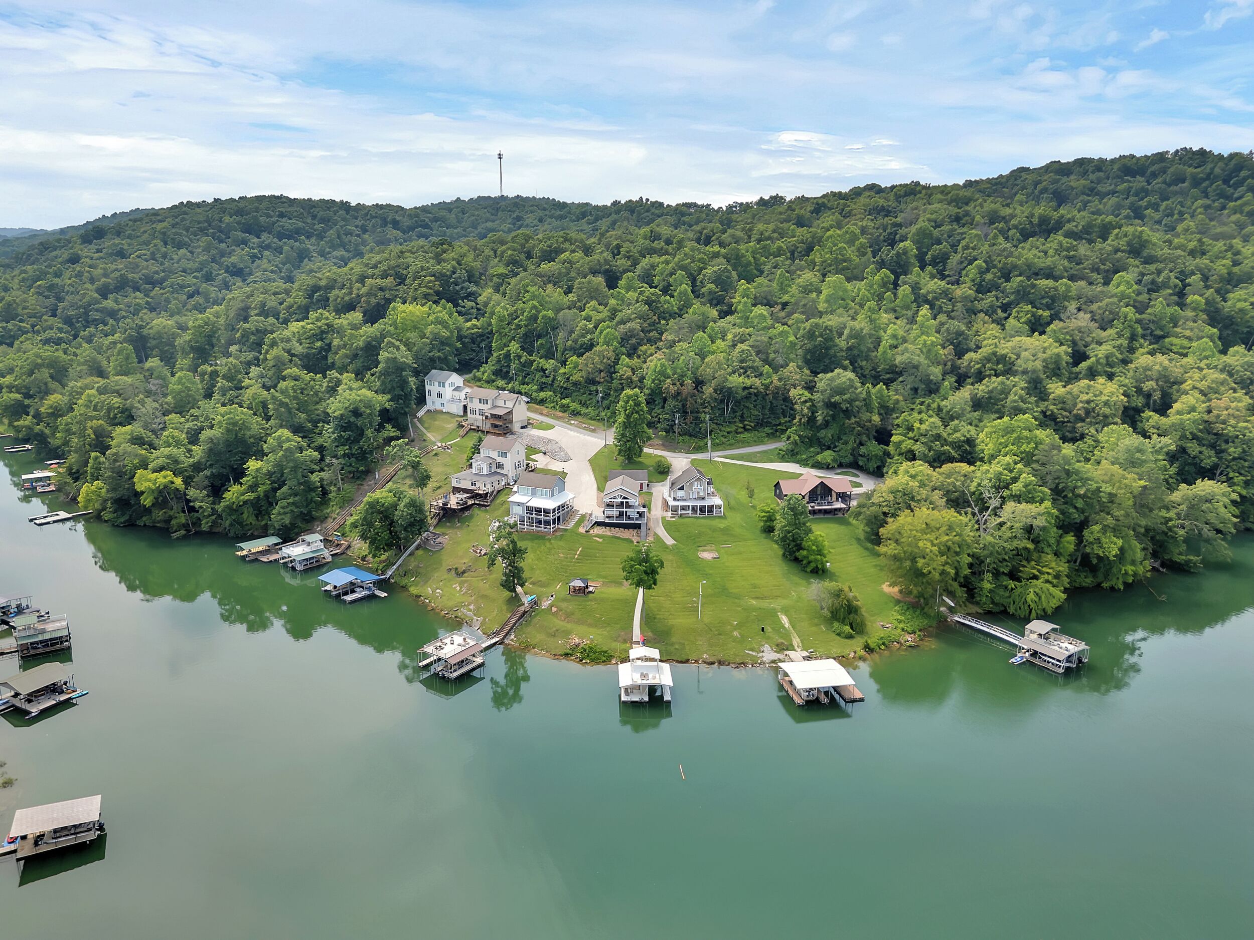 An aerial view of a lakeside property with multiple houses, docks, and boats.