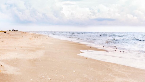 Ein Strand mit sandigem Ufer und Wellen.