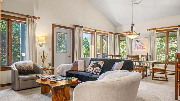 A spacious living room with a sofa, armchairs, a coffee table, and a dining area with chairs and a table. - RMR: Rendezvous A5 Condo in Teton Village (Teton Village)