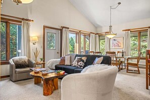 A spacious living room with a sofa, armchairs, a coffee table, and a dining area with chairs and a table. - RMR: Rendezvous A5 Condo in Teton Village (Teton Village)