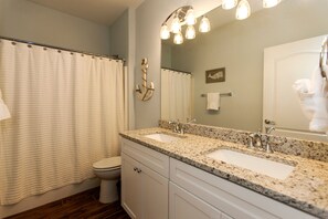 A bathroom with two sinks, a toilet, and a shower curtain. - Walk just 2 blocks to the beach! (PANAMA CITY BEACH)