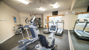 Una palestra con diverse attrezzature per esercizi, un tapis roulant e uno specchio a parete.