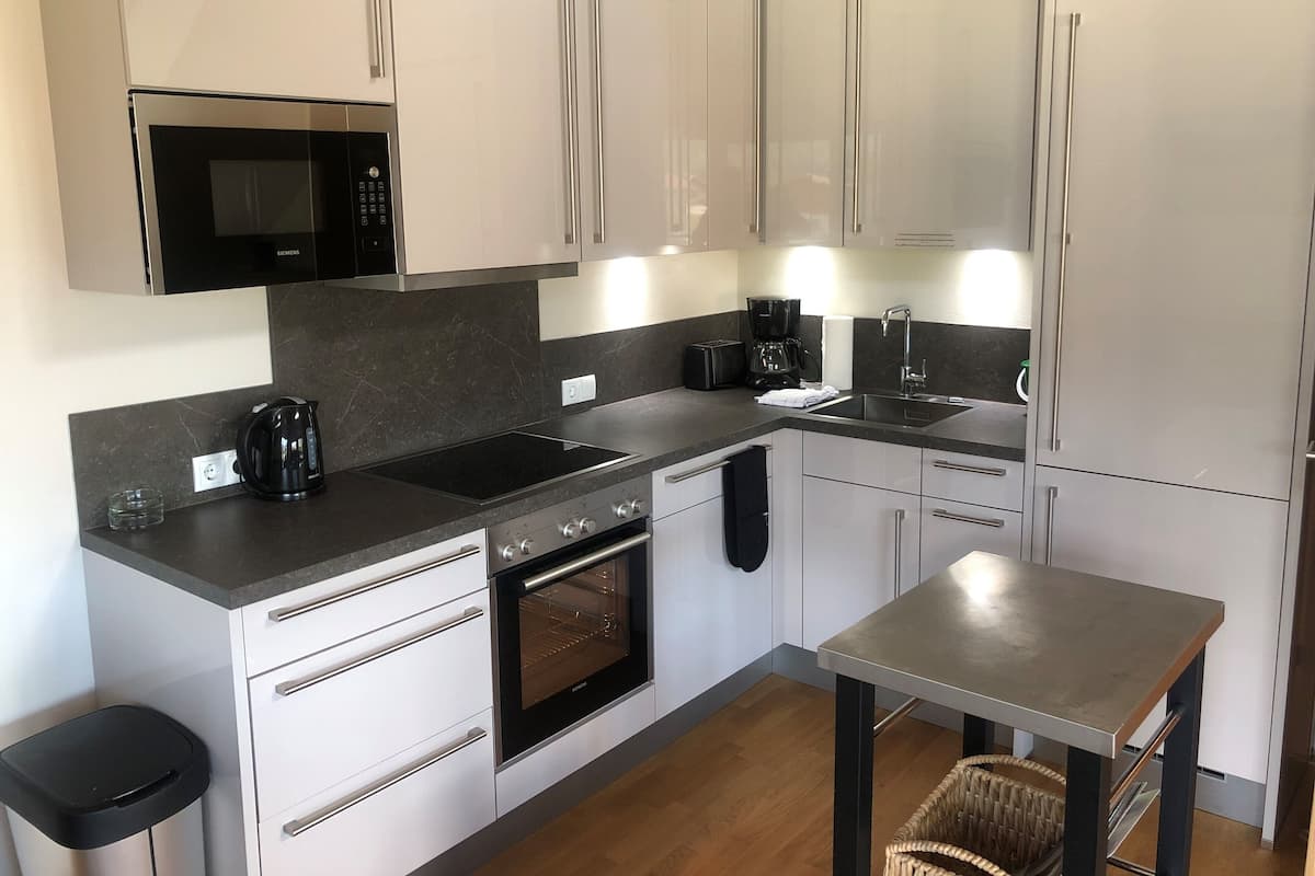 Een moderne keuken met roestvrijstalen apparatuur, witte kasten en een eettafel.