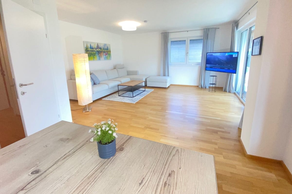 Een moderne woonkamer met een bank, salontafel en televisie.
