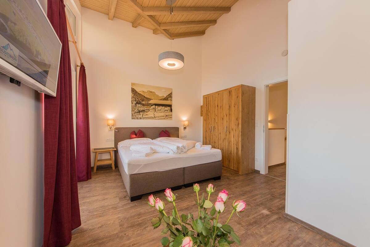 Een slaapkamer met een bed, een houten kledingkast en een schilderij aan de muur.