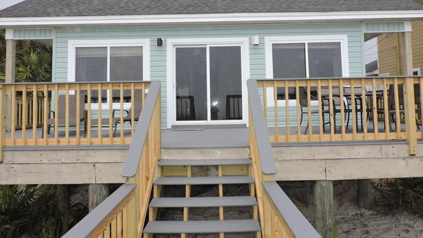 A two-story house with a front deck, a staircase, and a sliding glass door.